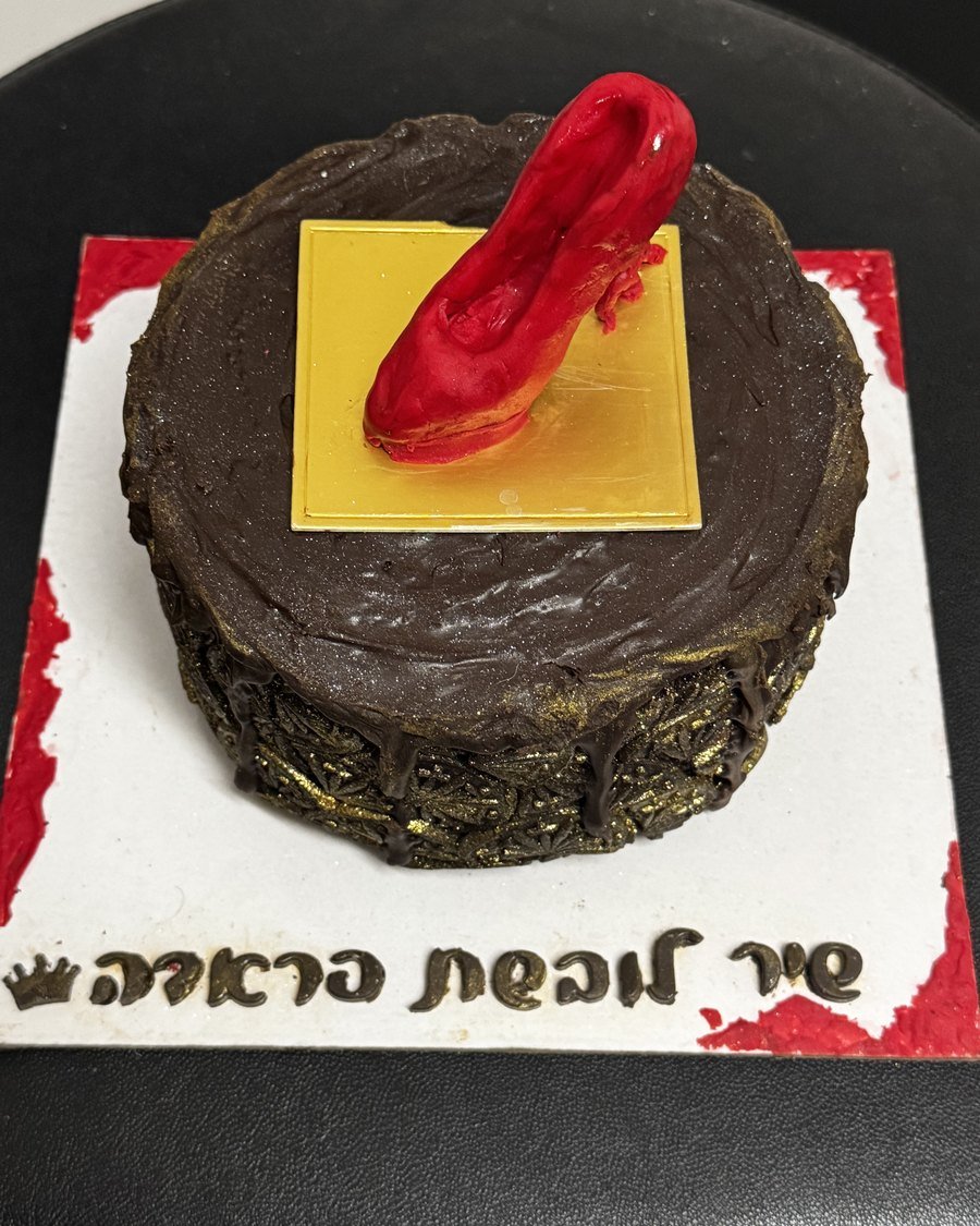 עוגת שוקולד מפוסלת עם נעל עקב אדומה על מדף מוזהב