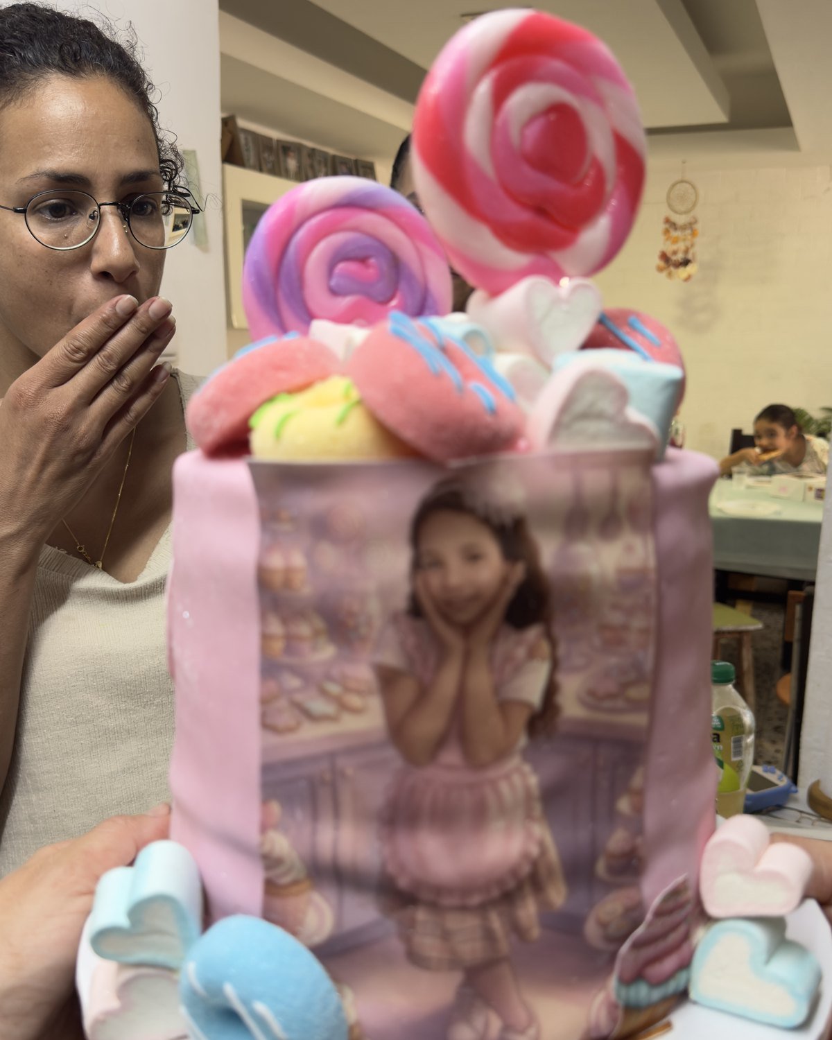 אמא מגיבה בהתרגשות לעוגת יום הולדת מעוצבת עם הדפס אישי של הילדה